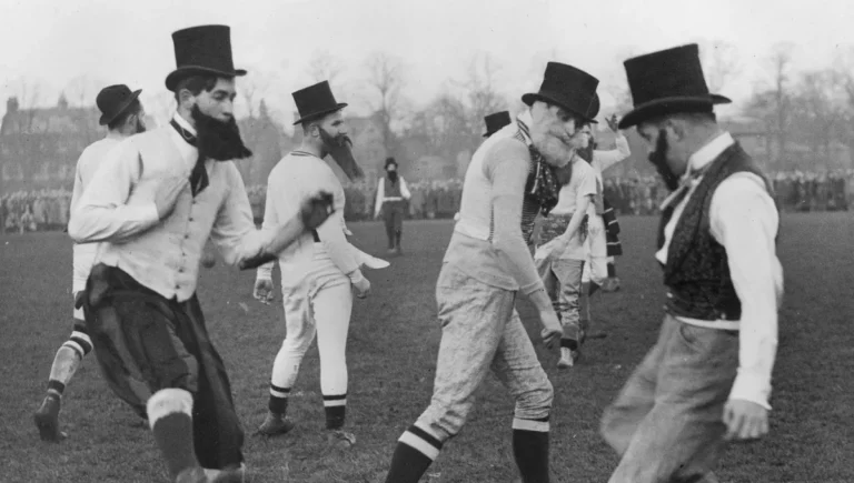 Match de football en Angleterre au XIXe siècle, joué par des hommes déguisés en bourgeois avec haut-de-forme et barbes postiches, symbole de l’origine élitiste et idéologique du sport.