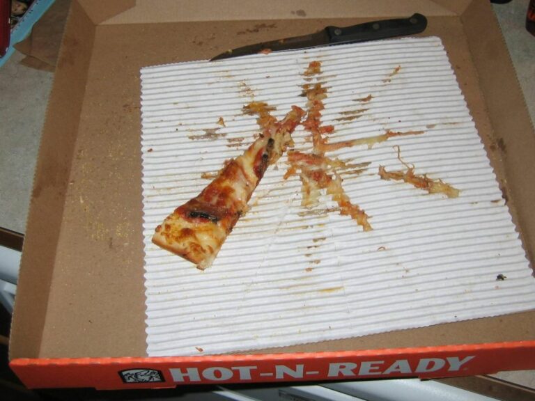 Boîte à pizza vide, sale et grasse, avec une seule part restante